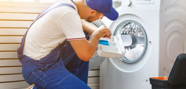 En installatör gör i ordning tvättmaskinen.
