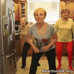 Tre äldre kvinnor dansar i ett kök